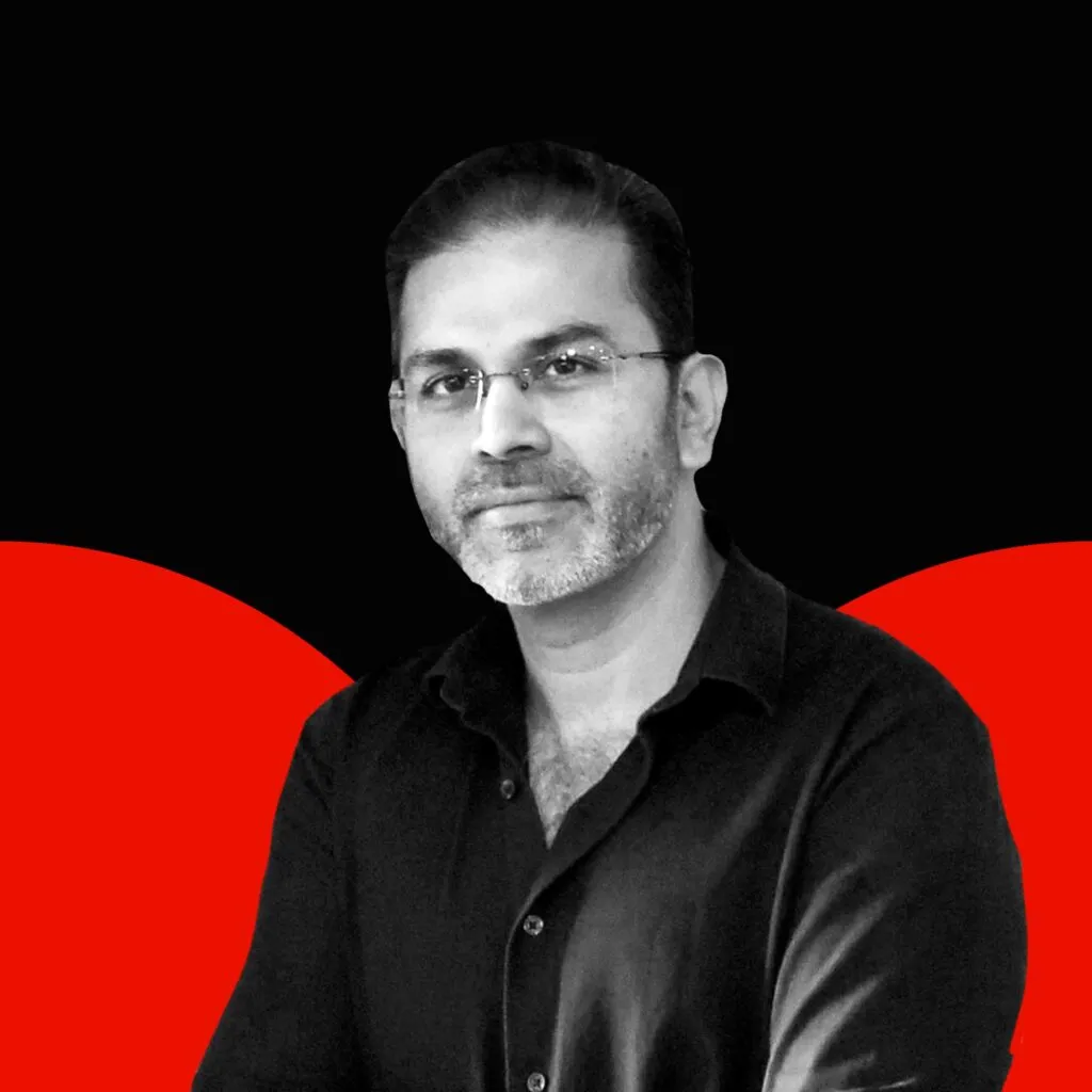 Black and white photo of Mahesh Gaitonde with red semi circles in the background